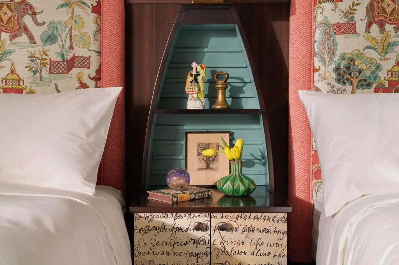 a bedroom with two beds and a side table with a mirror at Graduate by Hilton Cambridge in Cambridge